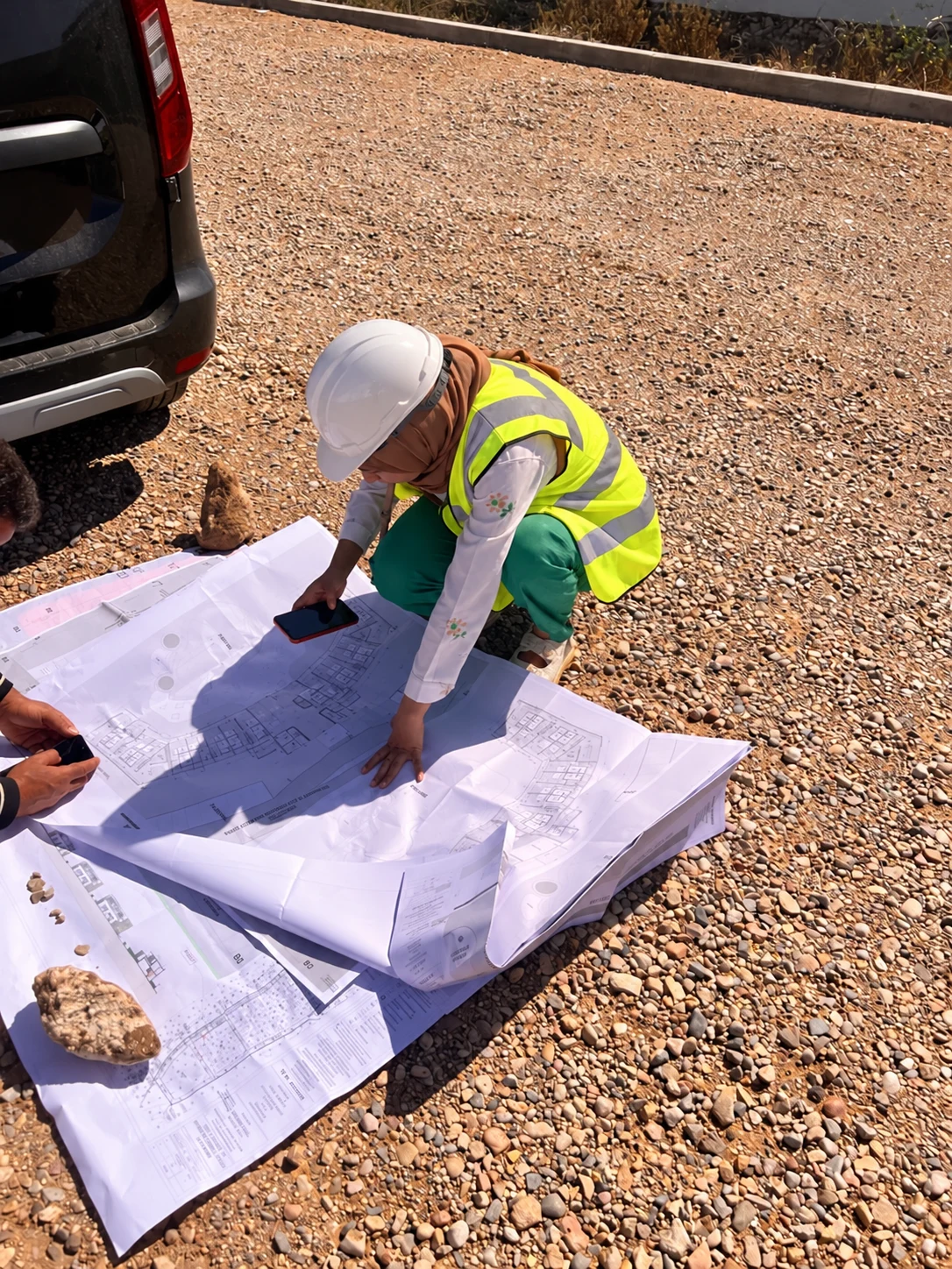 Lecture de plans sur le terrain, en tenue de sécurité